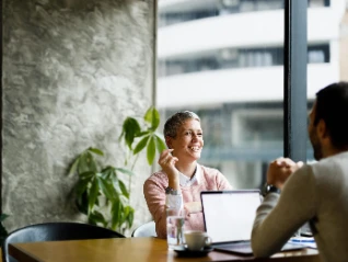 woman and man talking behind laptop right 