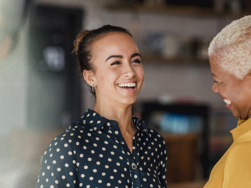Two females wearing bright clothes working in an office