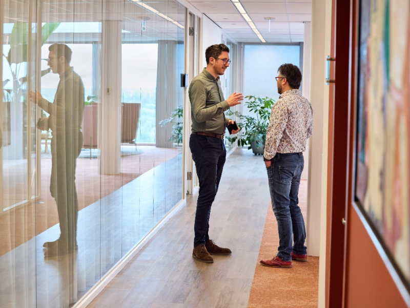 Two colleagues confer briefly in the corridor