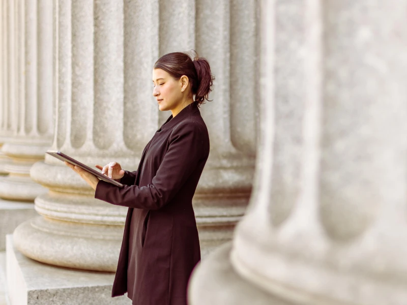 Businesswoman standing outside bank working on a tablet
