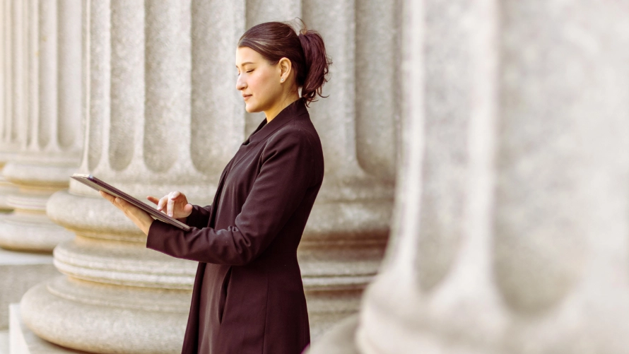 Businesswoman standing outside bank working on a tablet