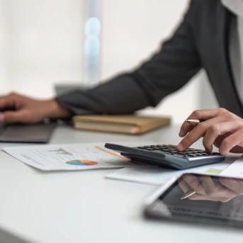 person using a calculator and laptop