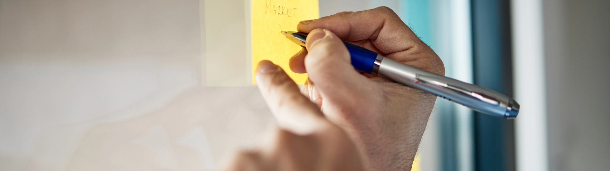 hands writing on post it note