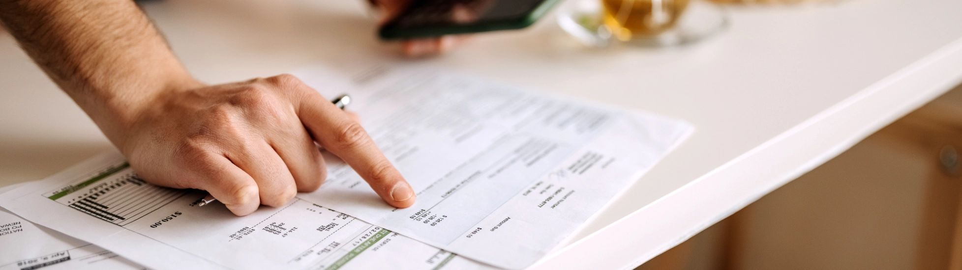 man pointing at sheet and holding mobile phone