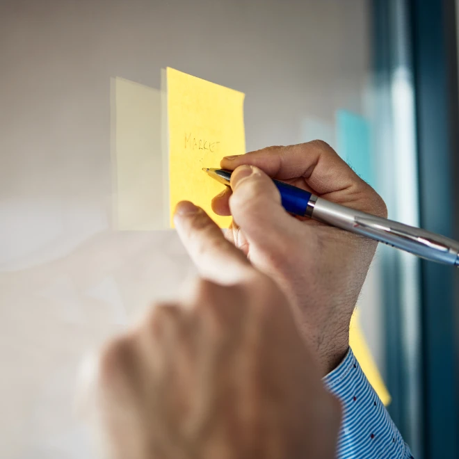hands writing on post it note