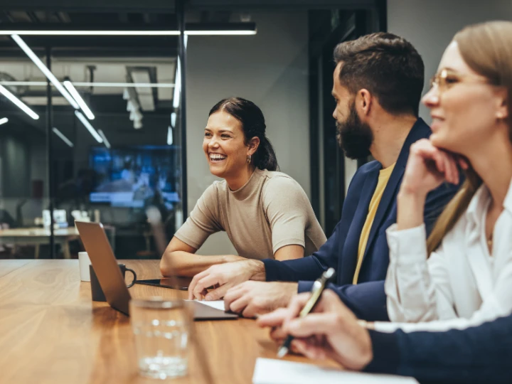 happy businesswoman laughing while leading a meeting with her colleagues
