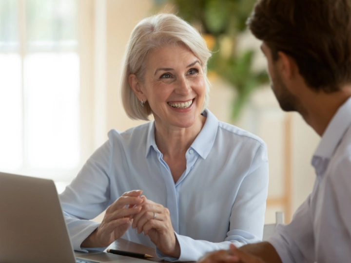 woman and man talking behind laptop