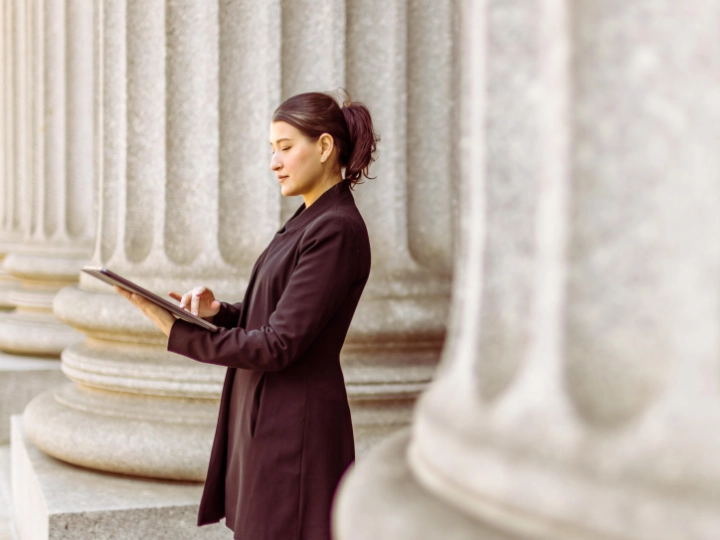 Businesswoman standing outside bank working on a tablet